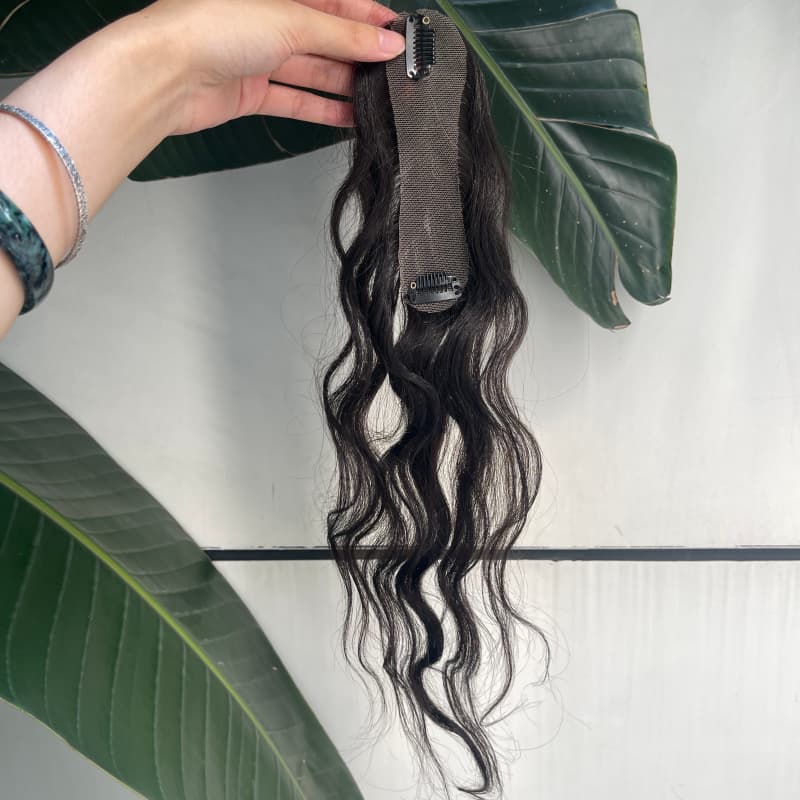 Black wavy clip-in hair topper on leaf